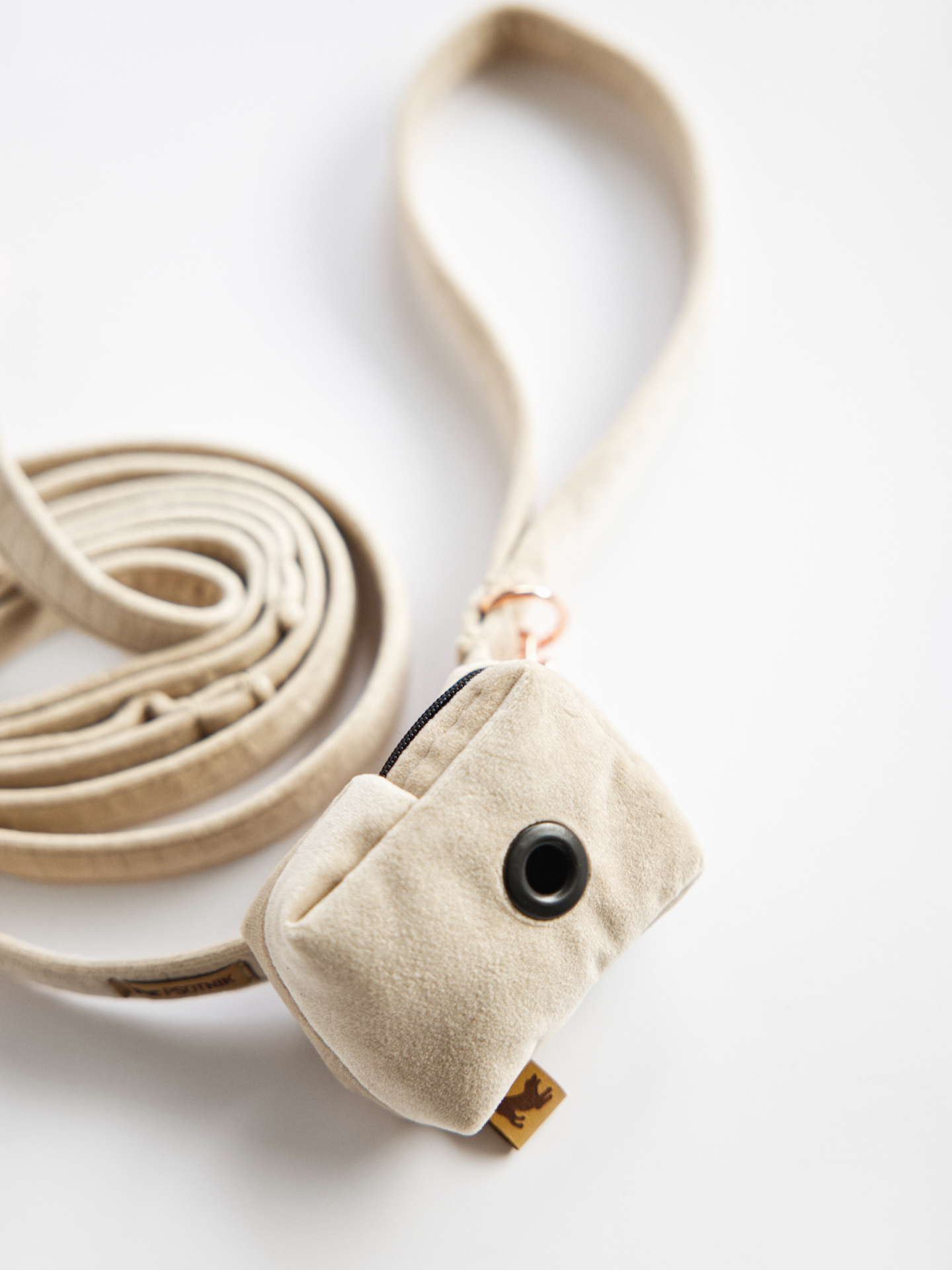 Welurowe etui na kupoworki w kolorze jasnego beżu założone na smycz